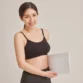 Woman standing and holding the medical-grade Red Light Abdomen Irradiator mat for home photobiomodulation therapy.